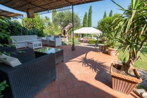 a patio with couches and tables and plants at Il Casale La Duchessa in Vetulonia