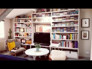 Una sala de estar con televisión, una mesa y libros. en Private heaven center Paris, en París
