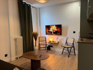 sala de estar con mesa, sillas y una pintura en Appartement Bien Équipé dans un Quartier Prisé, en Boulogne-Billancourt