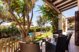a patio with chairs and a fence and trees at Villa Victoria By EscapeHome in Binibeca