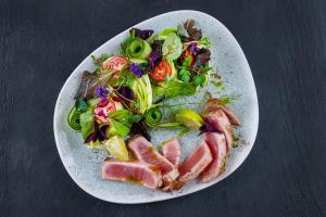 a plate of food with meat and salad on a table at Hotel Kiss in Tata +47 photos