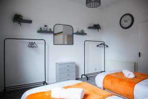 a bedroom with two beds and a clock on the wall at Spacious 2-Bedroom Flat with 4 Beds, Ideal for Contractors, Long Stay Deals in Wallasey