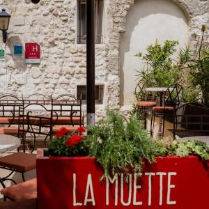 an outdoor patio with tables and chairs and flowers at Hôtel La Muette in Arles