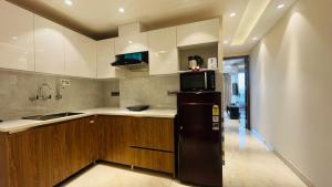 a kitchen with a black refrigerator and wooden cabinets at ZEN Suites Gurgaon - LUXE Stays Collection in Gurgaon