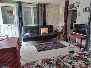 a living room with a black couch and a table at DOMAINE du VIEUX MOULIN in Westhalten