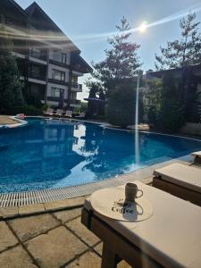 a coffee cup sitting on a table next to a swimming pool at Aspen Suites Luxury Studio A006 in Razlog