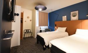a hotel room with two beds and a chair at ibis Laval Le Relais D'Armor in Laval