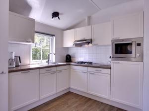 a white kitchen with white cabinets and a microwave at Holiday Home 4-persoons bos-3 by Interhome in Dalfsen +19 photos