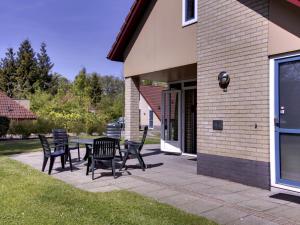 a patio with chairs and a table next to a building at Holiday Home 4-persoons by Interhome in Dalfsen