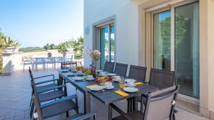 a table on a patio with chairs and food on it at VILLA BIANCA 10, Emma Villas in Misano Adriatico
