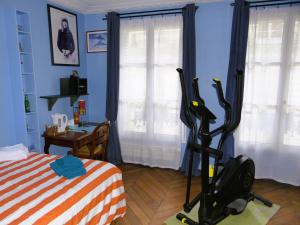 a bedroom with a treadmill in front of a bed at Bergère Opéra Trévise - 2 connecting rooms with private bathroom and 1 study room - 35 m2 in Paris