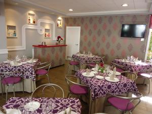 une salle à manger avec des tables, des chaises et un chiffon de table violet dans l'établissement Hostal Calderón de la Barca, à Zalamea de la Serena