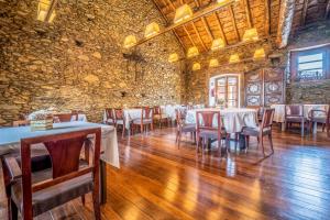 a dining room with tables and chairs and a stone wall at Fonda dels Pics in Escardacs