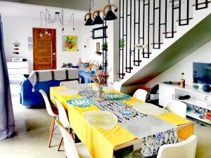 comedor con mesa amarilla y sillas blancas en Villa Grain de café, 4 chambres piscine accès plage, en Trou aux Biches