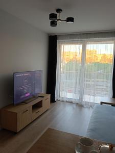 ein Wohnzimmer mit einem Flachbild-TV auf einem Holzschrank in der Unterkunft Przystań Klonowa in Kielce