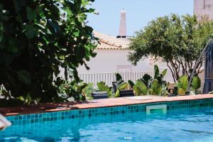 ein Pool mit Stühlen und Bäumen neben einem Gebäude in der Unterkunft Old Fisherman's Corner 18 - Centro Old Town Albufeira in Albufeira