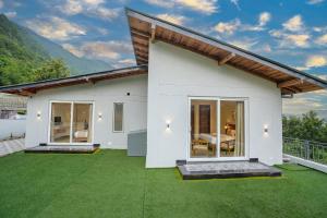 a white house with a green lawn at SaffronStays Bourbon in Bhīm Tāl