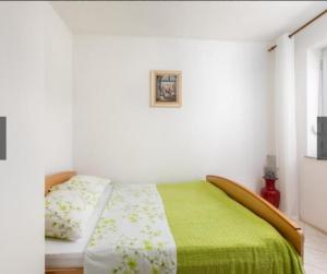 a bedroom with a bed with a green blanket at Two Bedroom Apartment Sonja with Seaview in Punat
