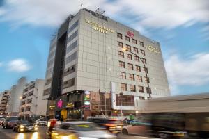 Lotus Grand Hotel في دبي: مبنى طويل وبه سيارات على شارع المدينة
