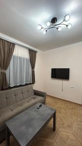 a living room with a couch and a flat screen tv at 4cosy apartment with view Ararat in Gukasavan