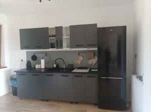 a kitchen with black cabinets and a black refrigerator at Sosnówka in Krutyń +10 photos