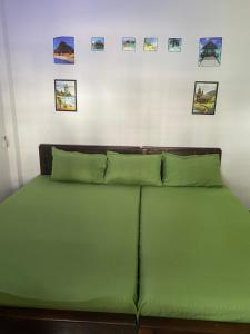 a green bed in a room with pictures on the wall at Beach Guest House Addalaichenai in Addalachenai