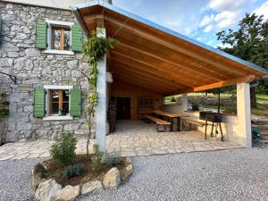 a stone house with a wooden roof and a patio at Mountain Lodge Istria - Stone Lodge II in Roč