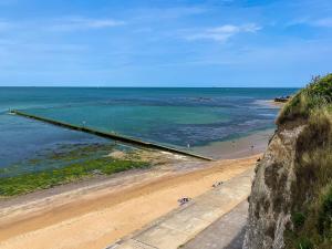 a beach with people on the sand and the ocean at Walpole Bay 2 Bed Stunning Garden Apt By Adliv in Margate