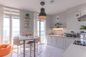 a kitchen with white cabinets and a table and chairs at Seaview Apt Turner Contemporary, Margate By Adliv in Margate