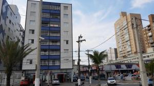 un edificio alto en una calle de la ciudad con palmeras en Prédio Frente Para o Mar Pé na Areia Lado Mercado Extra SEM VISTA MAR, en Praia Grande