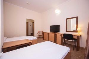 a room with two beds and a desk with a television at Optima Odesa in Odesa