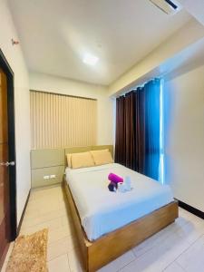 - une chambre dotée d'un lit avec un animal violet farci dans l'établissement Mactan cozy staycation, à Lapu Lapu City