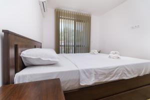 a bedroom with a large white bed with a wooden headboard at Modern 1-Bedroom Apartment with Free Parking in Plovdiv