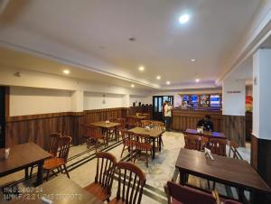 a restaurant with wooden tables and chairs and a person standing at the counter at Vyshak International in Payyannūr