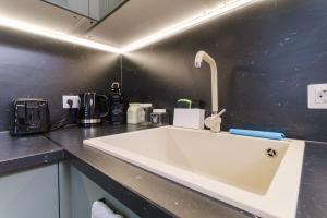 a white sink in a kitchen with a black wall at Modern 1-Bedroom Apartment with Free Parking in Plovdiv +20 photos