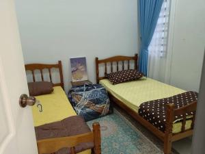 two twin beds in a room with a door at Ruls Homestay Kuala Nerus in Kampong Banggol Setol