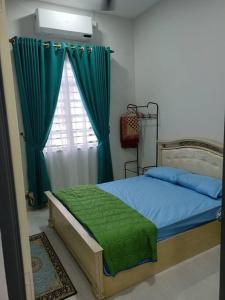 a bedroom with a bed and a window with green curtains at Ruls Homestay Kuala Nerus in Kampong Banggol Setol