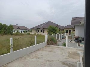 a fence in front of a yard with houses at Ruls Homestay Kuala Nerus in Kampong Banggol Setol