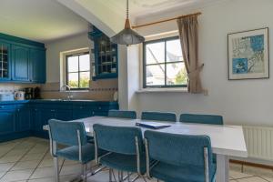 a kitchen with blue cabinets and a table and chairs at Buitenplaats 86 in Callantsoog