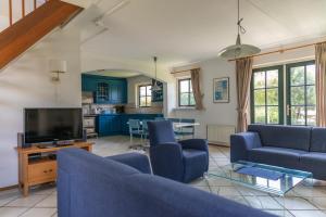 a living room with blue couches and a tv at Buitenplaats 86 in Callantsoog