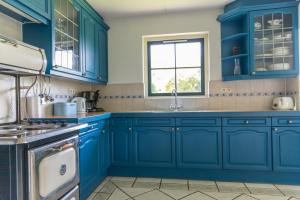 a kitchen with blue cabinets and a window at Buitenplaats 86 in Callantsoog