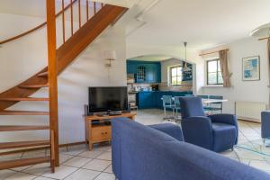 a living room with blue chairs and a television at Buitenplaats 86 in Callantsoog +10 photos