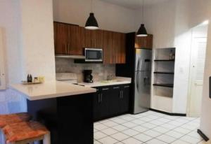 a kitchen with black cabinets and white tile floors at Cabo Oasis At Misiones in Cabo San Lucas