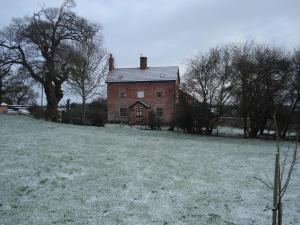an old brick house in a field with trees at Oak Tree Farm in Yoxford