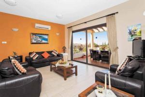 un soggiorno con divani in pelle e TV di Villa Melody Latchi a Neo Chorio