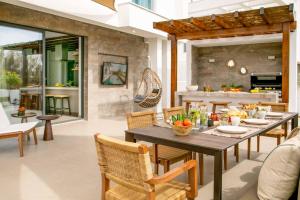 eine Terrasse mit Tisch und Stühlen und eine Küche in der Unterkunft Lora Pearl Luxury Villa in Protaras