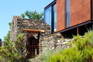 an old stone house with glass windows on a hill at InXisto Lodges in Piódão