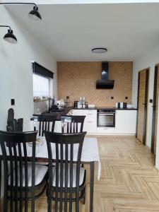 a kitchen with a table and some chairs in it at Domek letniskowy - Leśna chmurka - sauna, bania in Cewice