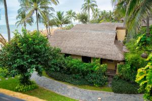 a house with a straw roof and a beach at Bamboo Village Beach Resort & Spa in Mui Ne