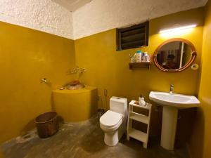 a yellow bathroom with a toilet and a sink at T Stop Farmhouse Coorg in Kurchi